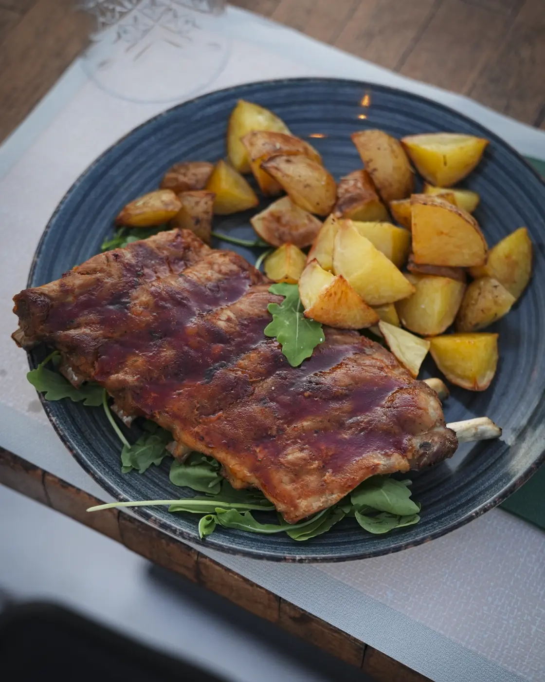 Ribs BBQ glassate servite su letto di rucola con patate arrosto